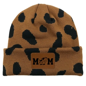 Detail of knitted cow print beanie with MOM leather patch and cute cow icon