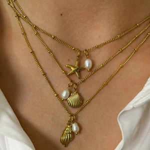 Three-layer gold necklace set featuring starfish, seashell, and white pearl ocean charms