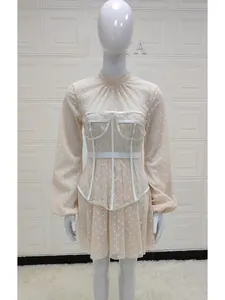 Close-up of elegant apricot chiffon dress with white polka dots and lace corset detail