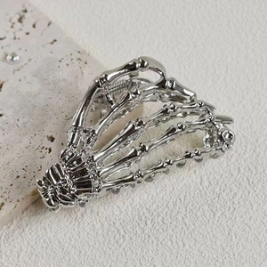 Close-up of silver metal spider web hair claw clip with a skeleton hand design