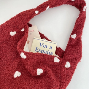 Dettaglio della borsa tote rossa in peluche con cuori bianchi e consistenza morbida