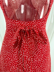 Close-up of the elegant open-back design with bow tie straps on this red polka dot dress