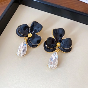 Detail of vintage flower earrings with black enamel and clear teardrop crystal
