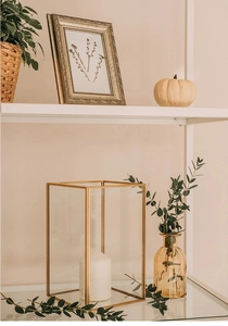 Detailed close-up of a modern gold metal frame glass candle holder with a white pillar candle