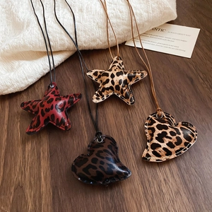 Detail view of leopard print star and heart leather pendants with visible stitching details