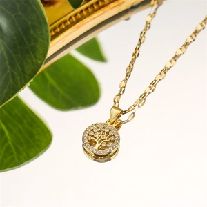 Close-up of golden Tree of Life pendant with sparkling zircons on reflective surface