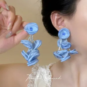 Close-up of light blue fabric flower drop earrings with layered organza petals and beads