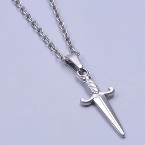 Macro detail of a silver stainless steel dagger pendant with cross guard on a link chain