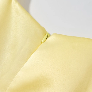 Makro-Detail von hochwertigem verdecktem Reißverschluss auf gelbem Satin-Kleidstoff