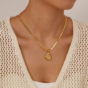Macro shot of a gold-toned conch shell pendant on a sleek snake chain necklace for women