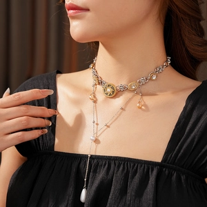 Close-up of a layered gold and silver necklace featuring a pearl drop and crystal pendant