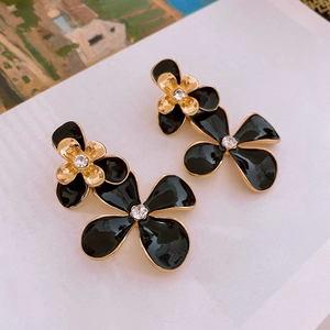 Detailed macro view of black and gold flower earrings with sparkling crystal centers