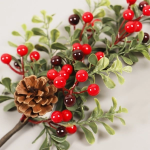 Christmas decorative branch with red berries, pine cones and green leaves on grey background