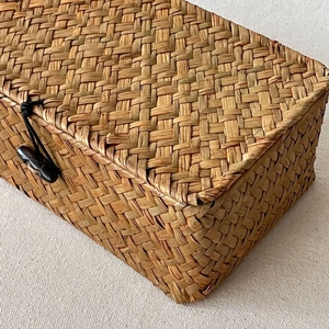Close-up of rectangular seagrass woven storage basket with lid and black button closure