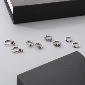 Detailed view of vintage silver-tone skull, rose, and cobra earrings on grey surface
