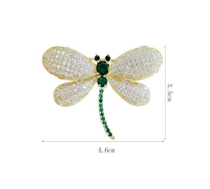 Detailed view of dragonfly brooch with green gems and white crystals, 4.6cm wide size