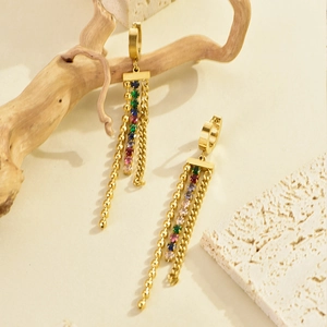 Detailed shot of long gold tassel earrings with colorful rhinestones on a wooden stand