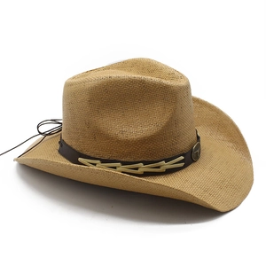 Close-up of a straw cowboy hat with a brown leather belt and vintage metal ornaments