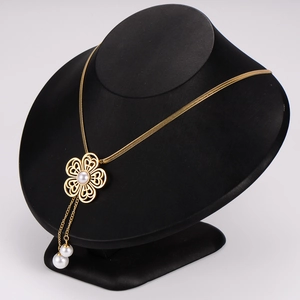 Elegant gold flower necklace with white pearl tassels on a black jewelry mannequin