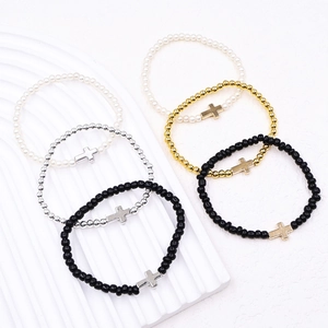 Detail of six-piece beaded bracelet set featuring faux pearls and cross pendants