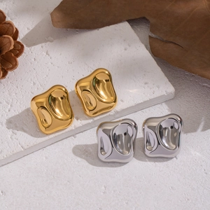 Detailed view of wave-textured gold and silver square stud earrings on white stones