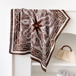 Detail of silk-like scarf with brown and white paisley print hanging on a rack