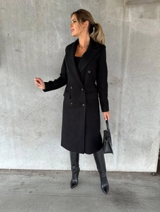 Full view of women's black double-breasted coat with long boots and leather handbag