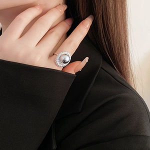Detailed view of an oval silver pearl ring with double pave zircon halo on a hand