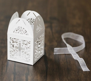 Close-up of white hollowed-out cross candy box with an elegant organza ribbon