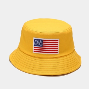 Detail of yellow cotton bucket hat featuring an American flag embroidery patch on front