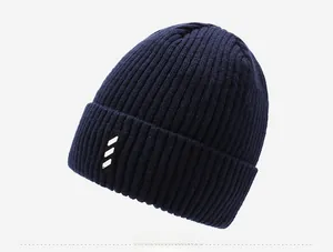 Macro detail of navy knit beanie with ribbed texture and striped woven label detail