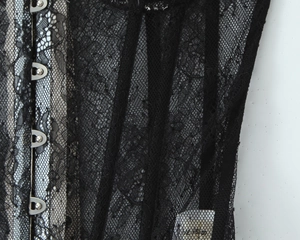Detail of black floral lace corset with vertical boning and silver metal busk closure