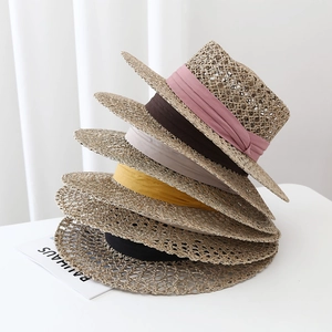 Stack of hollow hand-woven seagrass sun hats with five colorful ribbon decorations