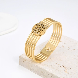 Detailed view of a gold multi-layer hollow bracelet with crystals on a stone tray