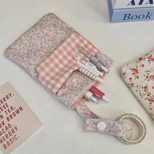 Close-up of floral and plaid fabric nurse pouch with snap strap on a clean desk
