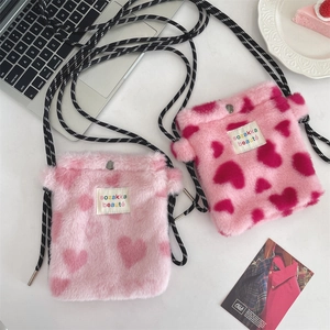 Detailed close-up of plush heart crossbody bags in pink and fuchsia with soft faux fur