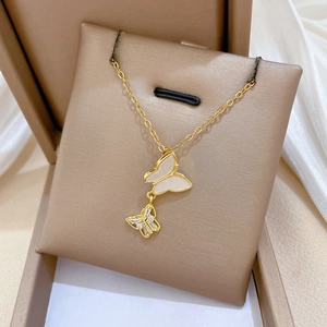 Dettaglio della collana a farfalla dorata con madreperla e accenti di cristallo