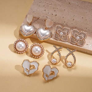 Detail of 5-pair gold earring set with faux pearls, floral studs and tulip drop earrings