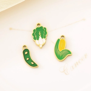 Detail view of colorful enamel vegetable charms featuring cabbage, pea pod and corn