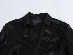 Detail of black mesh shirt featuring 3D flower appliques and classic collar design