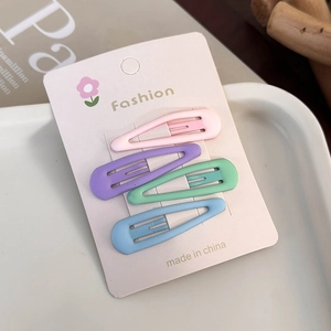Close-up of four macaron-colored teardrop hair clips with a matte finish on a card
