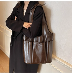 Detail of dark brown faux leather tote bag showing two front pockets with round buttons