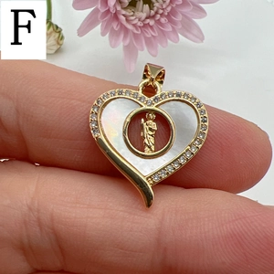 Macro view of gold heart pendant with white mother of pearl and Guadalupe saint detail