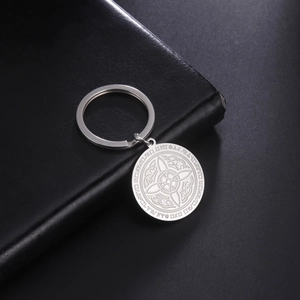 Polished stainless steel keychain with Celtic knot pendant on black leather notebook