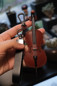 Detail of brown leather violin keychain with black strap and metallic ring