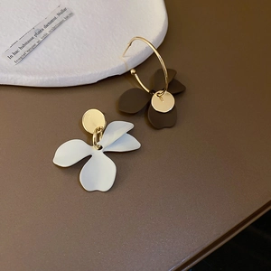 Détail de boucles d'oreilles fleurs asymétriques en or avec pétales mats élégants