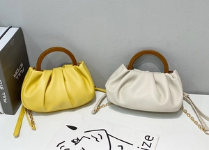 Detail of ruched cloud bags in lemon yellow and off-white with round wooden handles