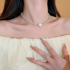 Detail of silver geometric chain choker with a large white pearl on a model neck