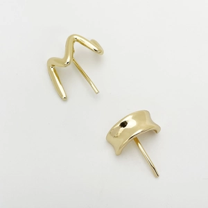 Detailed view of wave-shaped and C-shaped golden alloy stud earrings on white background