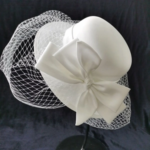 Elegant white bridal pillbox hat with oversized bow and mesh veil for formal events
